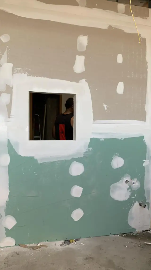 Parede em drywall com placa verde e abertura de passagem na clínica em Ilhéus