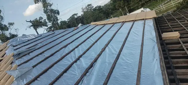 Manta térmica aluminizada instalada sobre o madeiramento na reforma de telhado em um sítio em Itajuípe