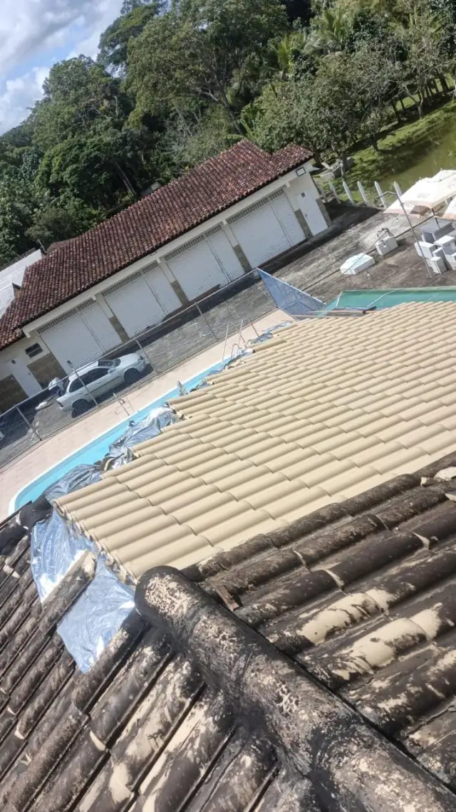 Trecho de telhado novo encontrando o antigo durante a troca, com a piscina ao fundo
